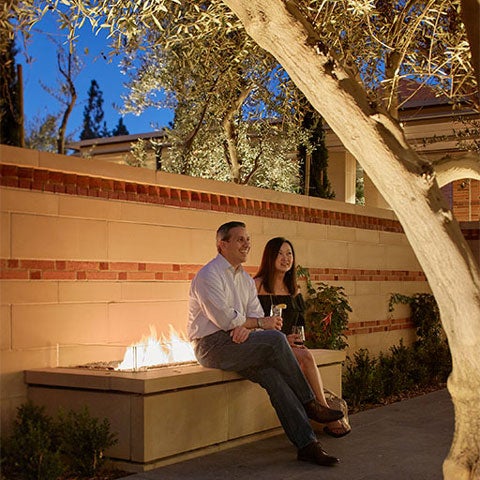 Two guests enjoying a drink at night on the outdoor patio near the outdoor fireplace.