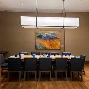 Large Private Dining Room 512×512 Private dining room with a long table, chairs, place settings, and a painting of a mountain on the wall.